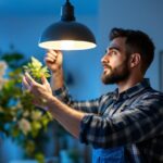A photograph of a skilled lighting contractor installing or adjusting a modern light fixture in a stylish home setting