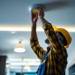 A photograph of a skilled lighting contractor installing or adjusting in-ceiling led fixtures in a modern interior space