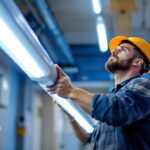 A photograph of a lighting contractor installing led fluorescent light tubes in a commercial space
