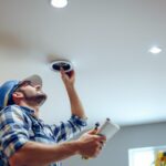 A photograph of a lighting contractor expertly installing shallow recessed pot lights in a modern ceiling