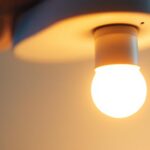 A photograph of a close-up of a gu24 base led light bulb being installed in a modern fixture