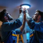 A photograph of a skilled lighting contractor updating recessed lighting in a modern home