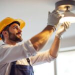A photograph of a lighting contractor expertly installing or adjusting a stylish russell lighting fixture in a modern